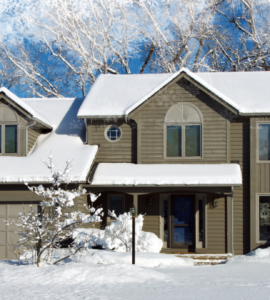 A large suburban home covered in a blanket of fresh, white snow.