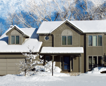 A large suburban home covered in a blanket of fresh, white snow.