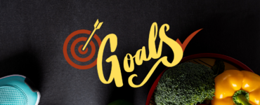 Image of heathy food and running shoes against a starck black background with the words, "Goals" written across the image.