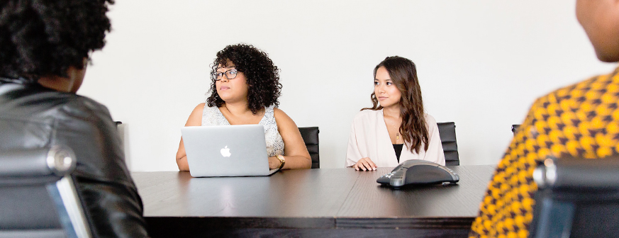 people sitting at a long table in a meeting