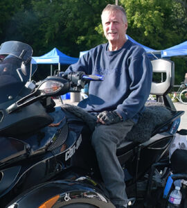 A man poses in front of a large custom four wheel all terrain vehicle.