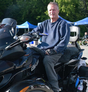 A man poses in front of a large custom four wheel all terrain vehicle.