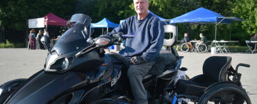 A man poses in front of a large custom four wheel all terrain vehicle.