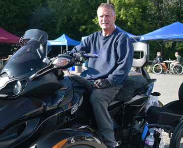 A man poses in front of a large custom four wheel all terrain vehicle.