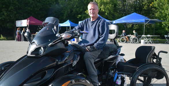 A man poses in front of a large custom four wheel all terrain vehicle.