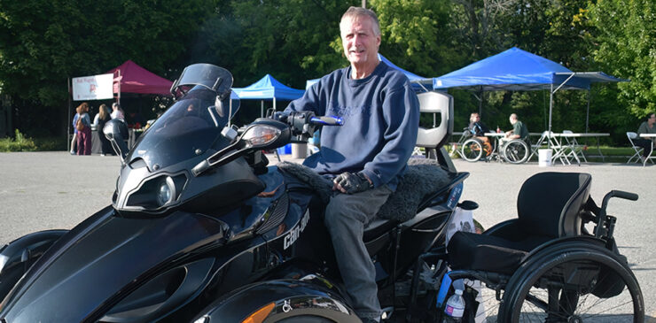 A man poses in front of a large custom four wheel all terrain vehicle.