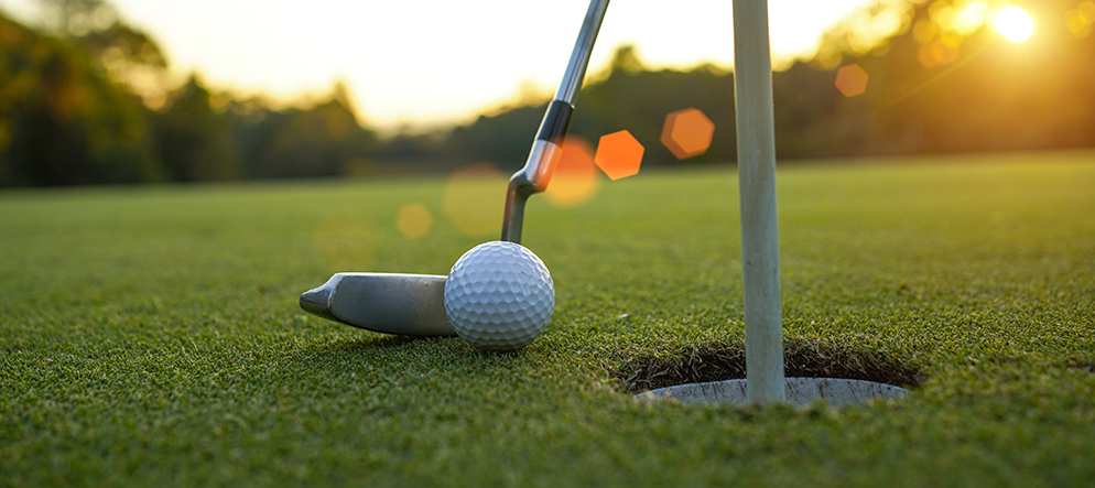 Close up of golf club and golf ball near hole