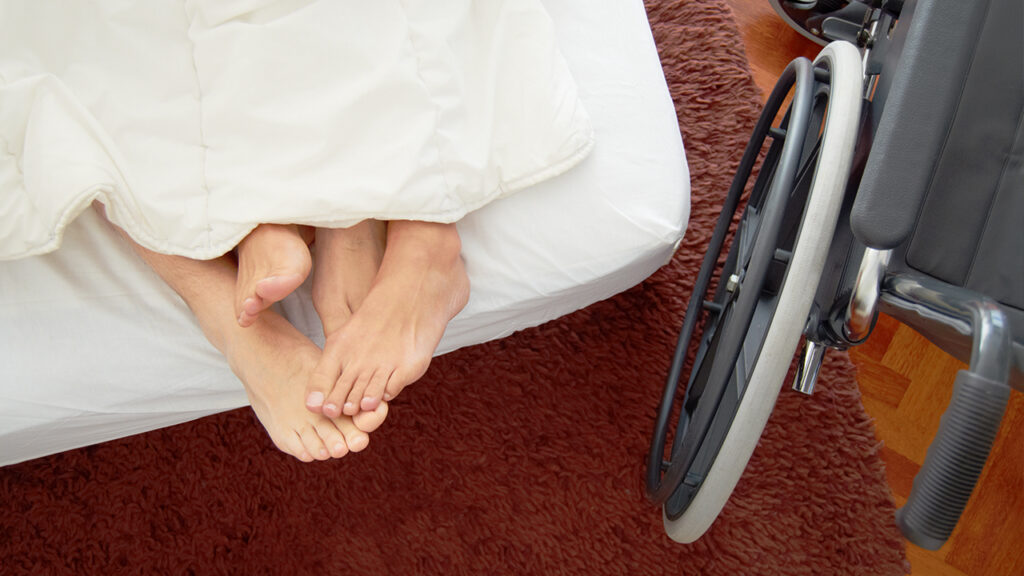 pair of naked feet between the sheets on a bed